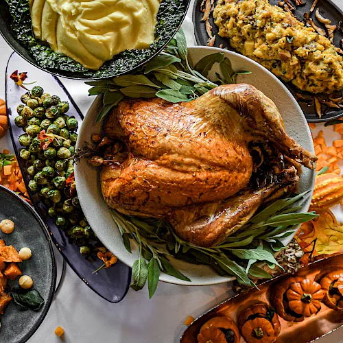 Roasted chicken with brussels sprouts, carrots, mushrooms, herbs, and other hearty sides on plates.