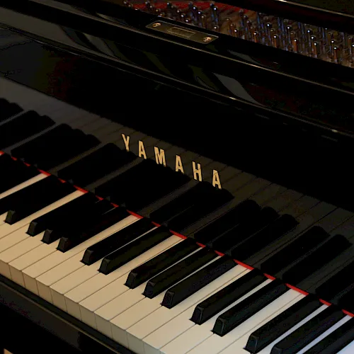A close-up of a piano keyboard with “YAMAHA” on the keys, framed by black and white keys and a polished interior background.