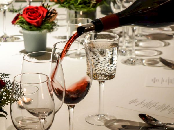 Elegant dining table with roses, wine pouring into a glass, and fine table.