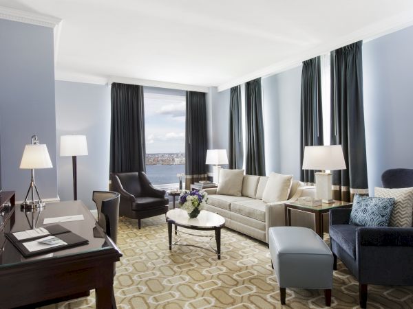 Elegant room with sofa, chairs, desk, lamps, and ocean view.