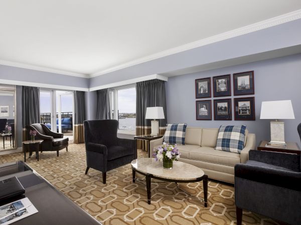 Elegant room with sofa, chairs, table, lamps, and harbor view.