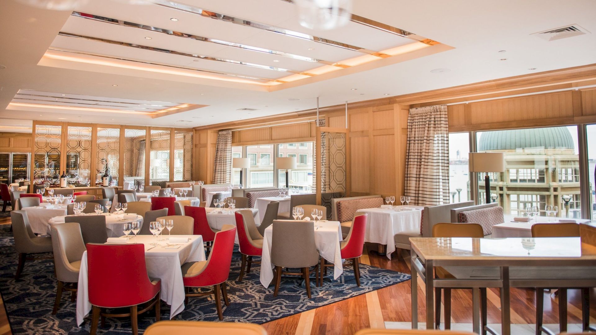 Elegant dining room with arranged tables, red and cream chairs, and modern lighting