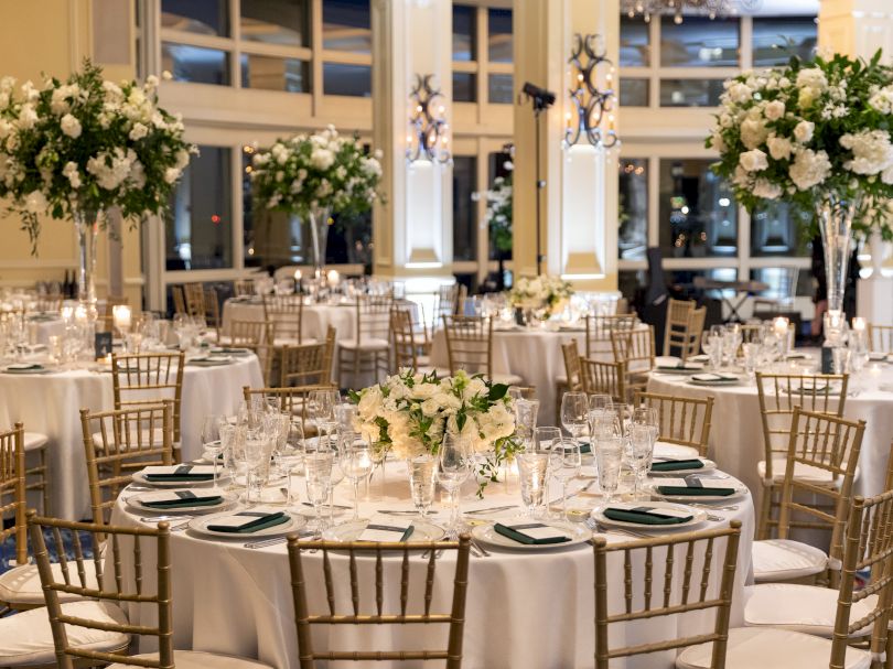 Elegant banquet hall set for an event with round tables, floral centerpieces,