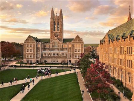 Historic university buildings at dusk with students walking.