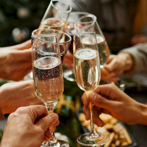 A group of people toasting with champagne flutes, celebrating together around a table with snacks.