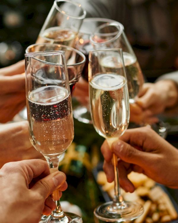 A group of people toasting with champagne flutes, celebrating together around a table with snacks.