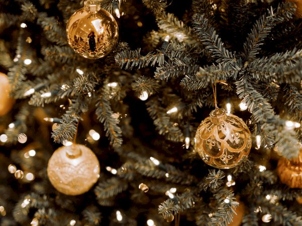 A Christmas tree adorned with gold ornaments and twinkling lights, creating a festive and warm holiday ambiance.