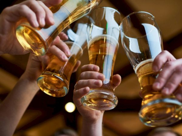 Several people are raising glasses of beer in a toast, likely celebrating or enjoying a social gathering.