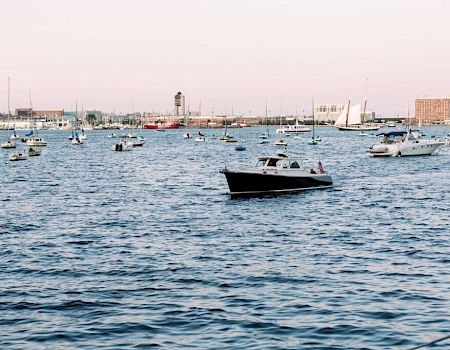The image shows numerous boats floating on a body of water near a cityscape with various buildings and structures visible in the background, ending the sentence.