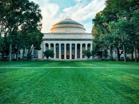 Classical dome building behind a lush green lawn.