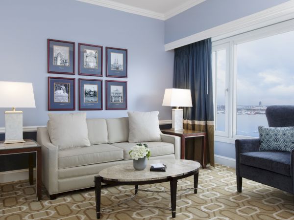A living room with a beige sofa, blue armchair, table, and lamps.