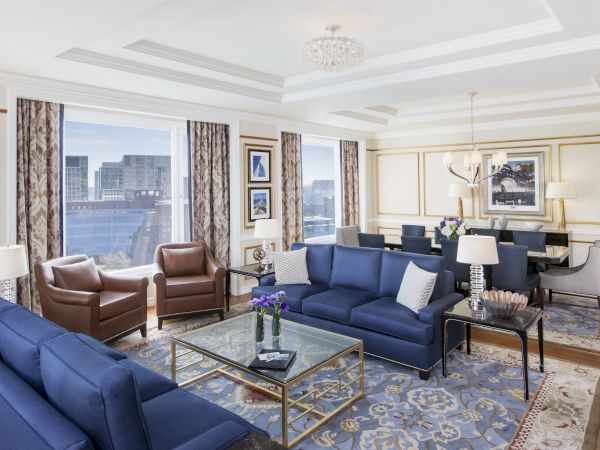 Luxurious room with blue sofas, chairs, chandelier, and city view.