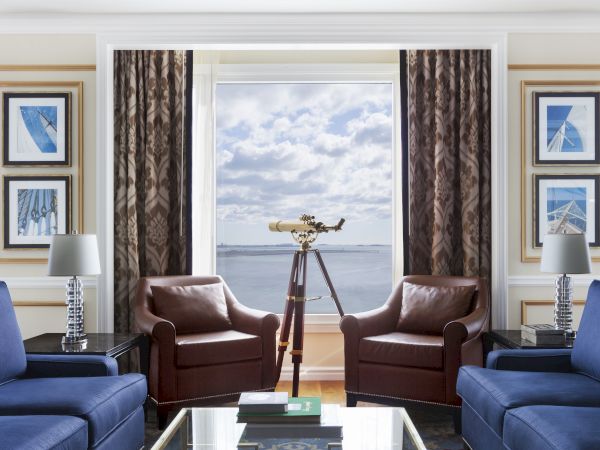 Elegant room with two blue sofas, a telescope, and harbor view.
