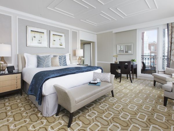 Elegant bedroom with a plush bed, art on walls, and cozy seating area.