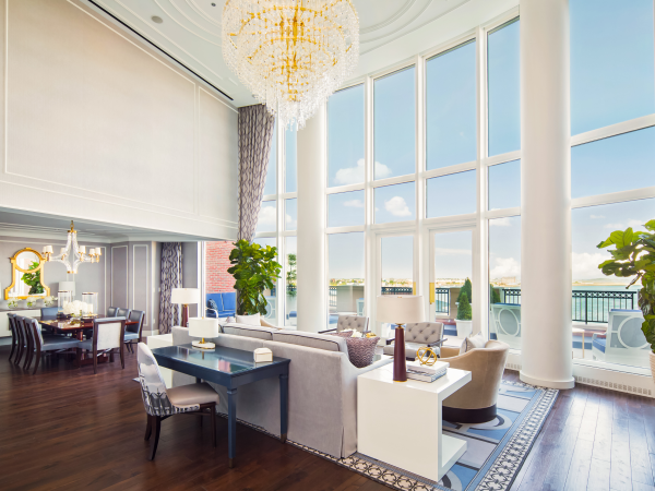 Elegant room with tall windows, plush seating, chandelier, and a dining table.
