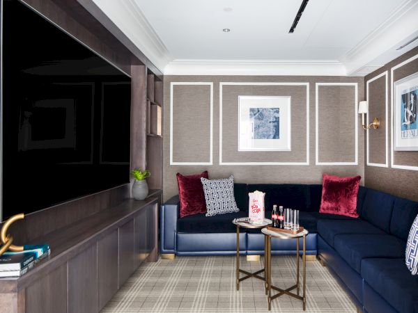 A modern room with a navy-blue sofa, television, framed art, and a coffee table.