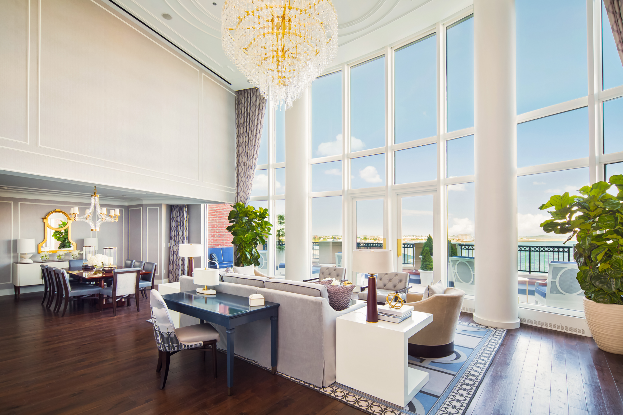 Elegant room with tall windows, plush seating, chandelier, and dining area