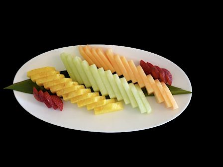 Sliced colorful fruit skewers arranged on a white plate with red garnish, presented on a black background.