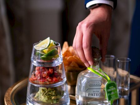 A person serves drinks and appetizers on a tray.