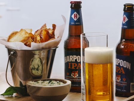 Beer bottles, a glass of beer, chips, and dip are visible on a
