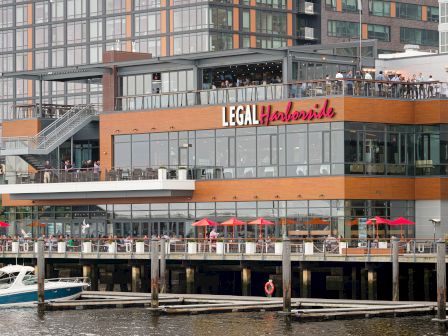 Waterfront building with "Legal Harborside" sign, umbrellas,