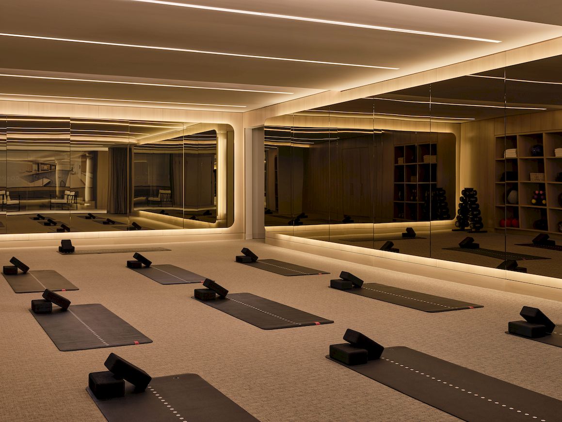Yoga mats and blocks arranged in a mirrored, softly lit studio for a calm, reflective practice session. End.