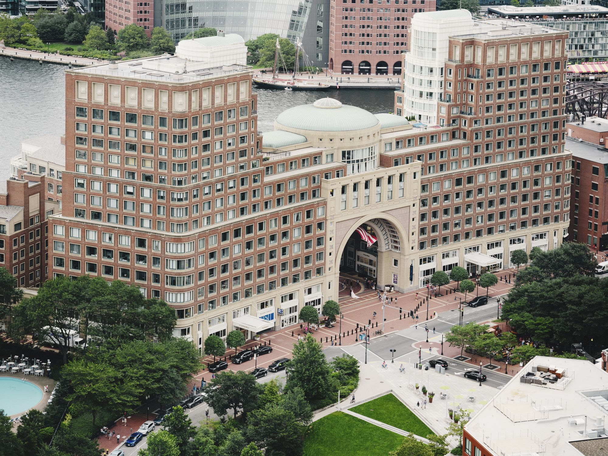 Aerial view of a large building with an arch, in front of an ocean.