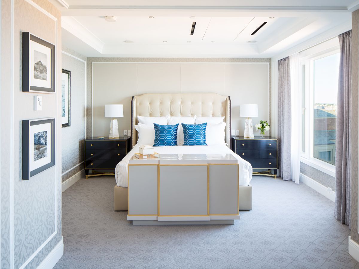 Elegant bedroom with a large bed, nightstands, lamps, and artwork.