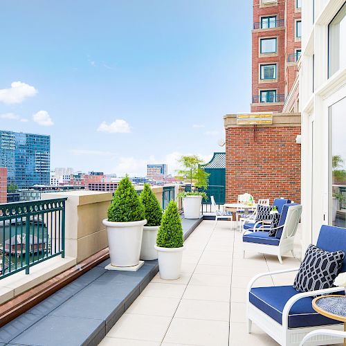 A balcony with chairs, plants, and a city view is pictured.