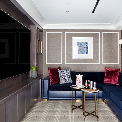 Modern room with a blue sofa, framed art, and a large TV.