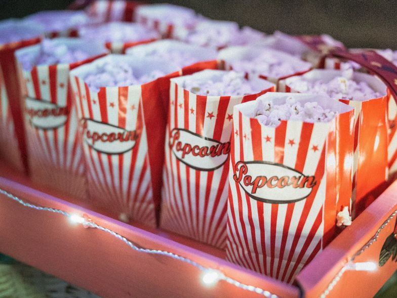Colorful striped popcorn bags filled with fluffy popcorn sit on a lit tray, ready for snacking.