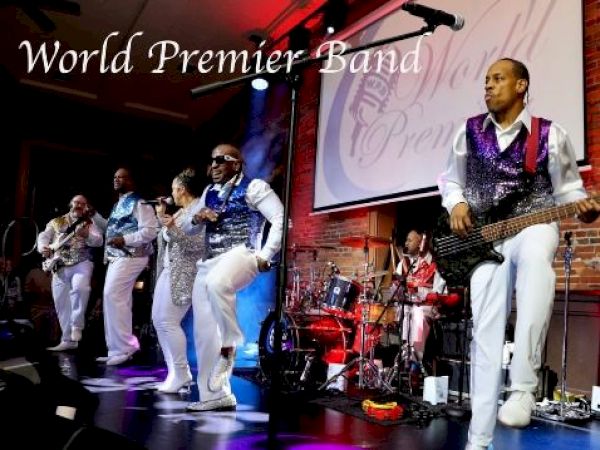 Photo of the stage where 5 band members are playing. Text across the top left reads "World Premier Band" which is the name of the band