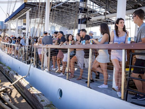People standing on a dock near a boat, enjoying a sunny day.