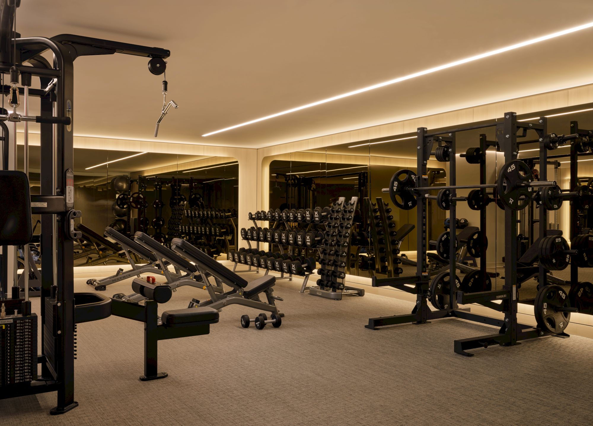 A well-equipped gym with squat racks, free weights, benches, and mirrors, ready for strength training and workouts.