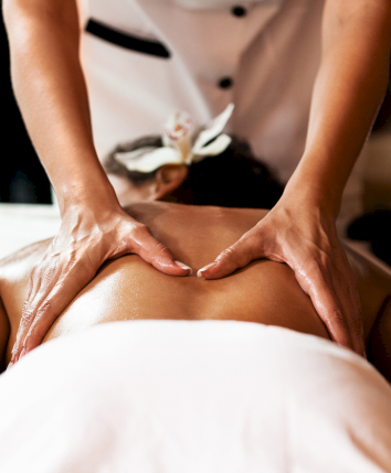 Back massage or spinal adjustment with hands pressing along the lower back, a relaxing spa treatment in progress.