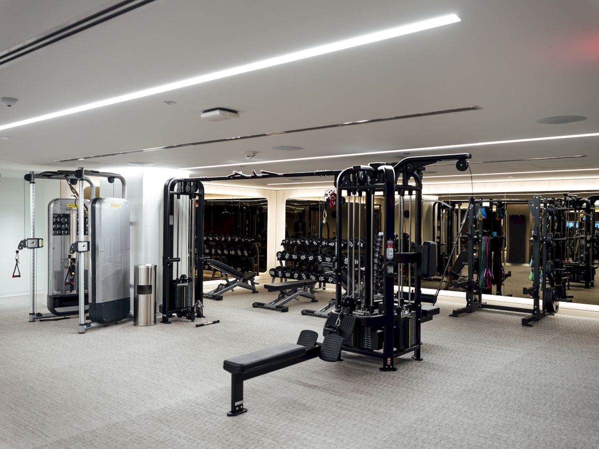 A gym with various exercise machines and weights, featuring mirrors and bright lighting.