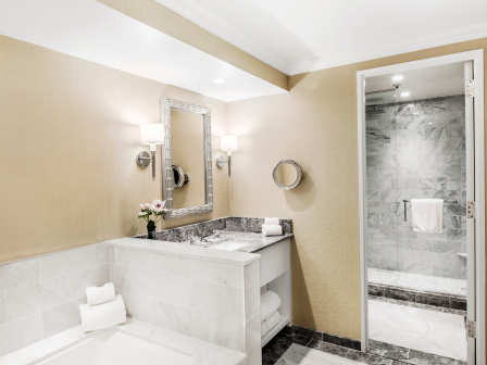 Modern bathroom with dual sinks, mirrors, and a glimpse of a shower area.