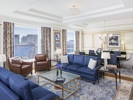 Luxurious room with blue sofas, chairs, chandelier, and city view.