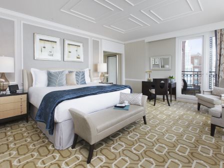 Elegant bedroom with a plush bed, art on walls, and cozy seating area.