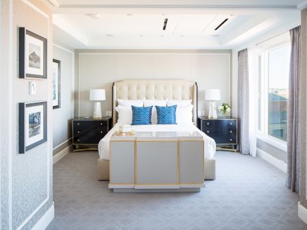 Elegant bedroom with a large bed, side tables, lamps, artwork, and window.