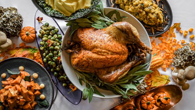 Roasted chicken with brussels sprouts, carrots, mushrooms, herbs, and other hearty sides on plates.