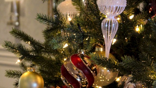 A decorated Christmas tree with warm gold lights and glass ornaments, including icicles, baubles, and snowflake-style decorations.