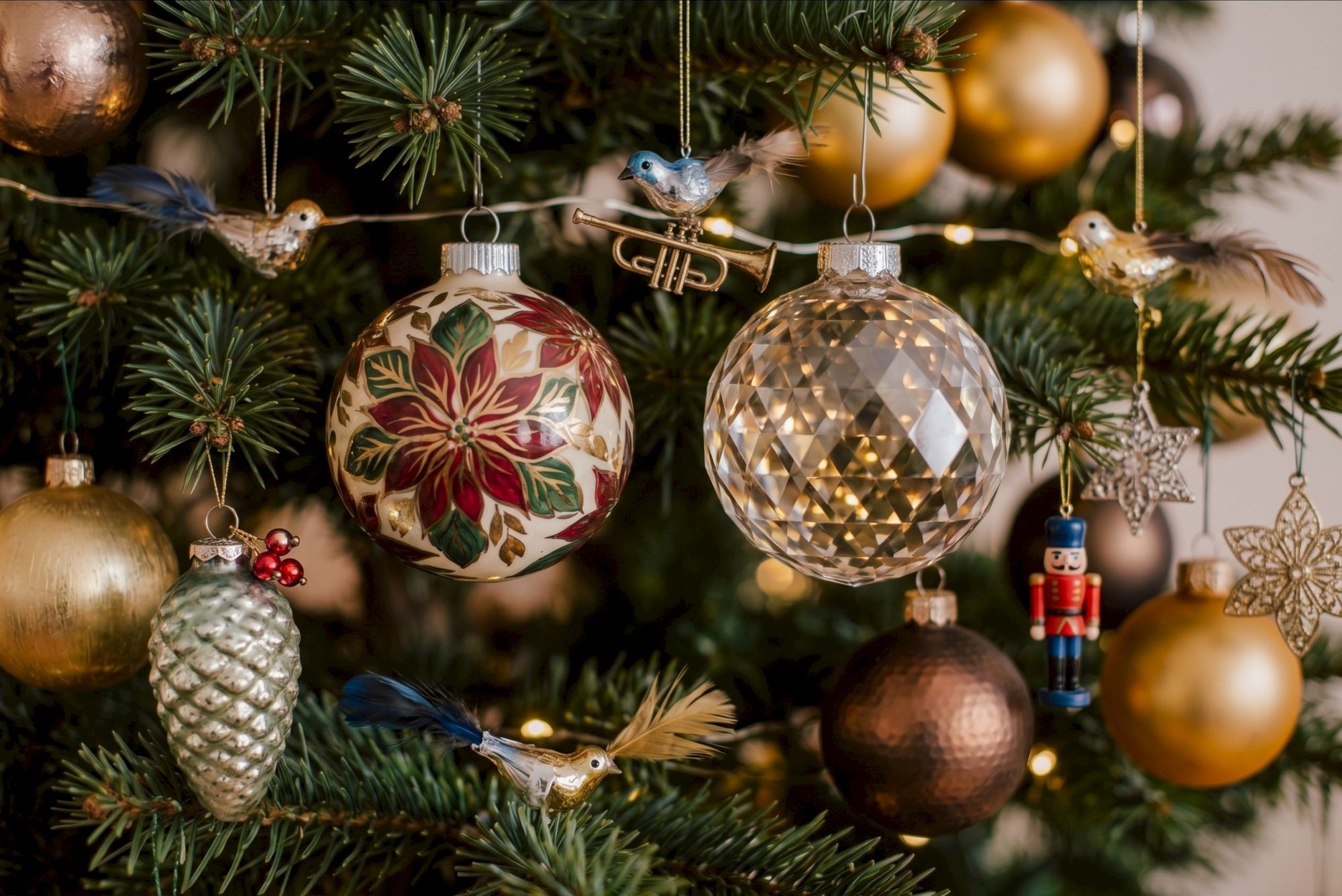 A decorated Christmas tree with hanging bird ornaments and gold, floral, and crystal-like baubles.