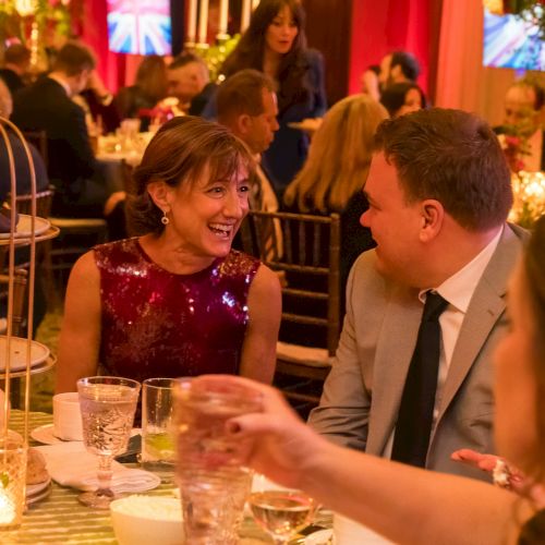 People are enjoying a formal dinner event with elegant decorations and flowers on the table, creating a warm and festive ambiance.