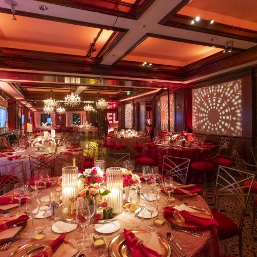 A beautifully decorated banquet hall with elegantly set tables, warm lighting, and intricate wall patterns creates an inviting ambiance.
