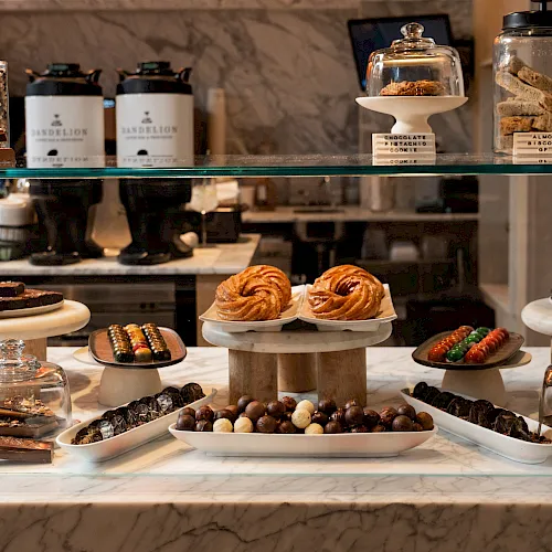 A dessert buffet display with chocolate treats, pastries, biscotti, and candy balls behind a glass case, ready to grab.