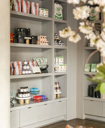 Shelves filled with various products, possibly skincare or wellness items, in a store setting with decorative flowers in the foreground.