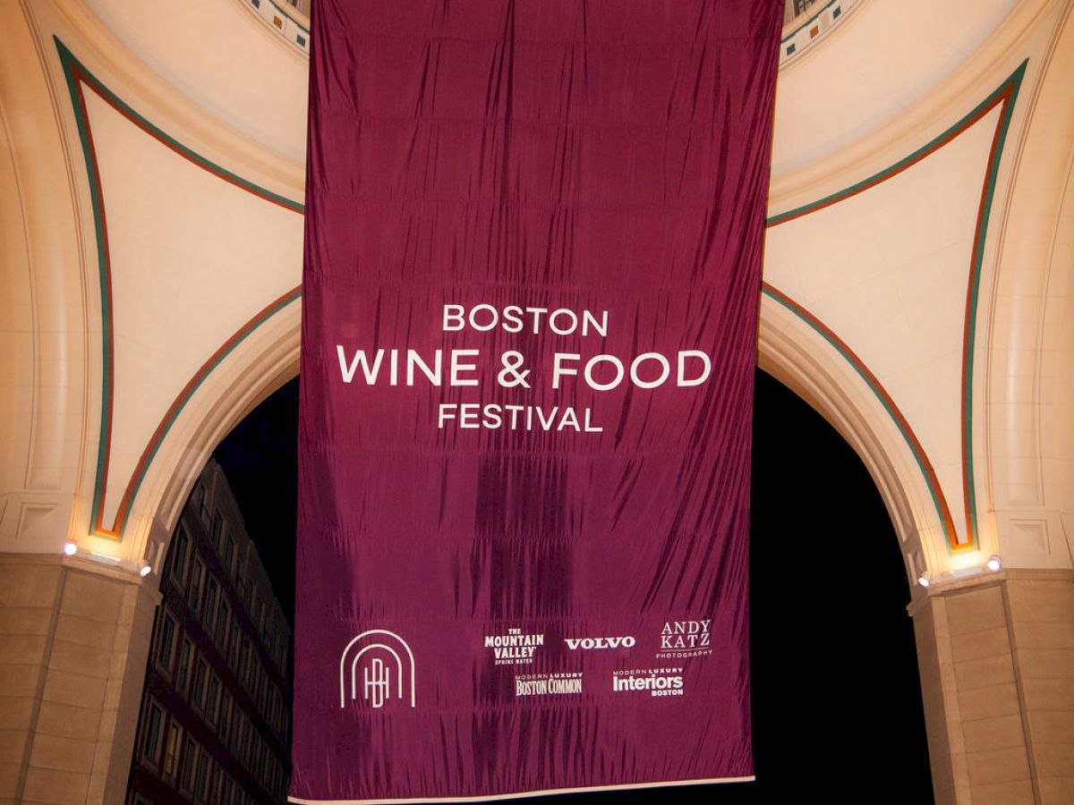 The image shows a large banner reading "Boston Wine & Food Festival" hanging in an archway with a car underneath.